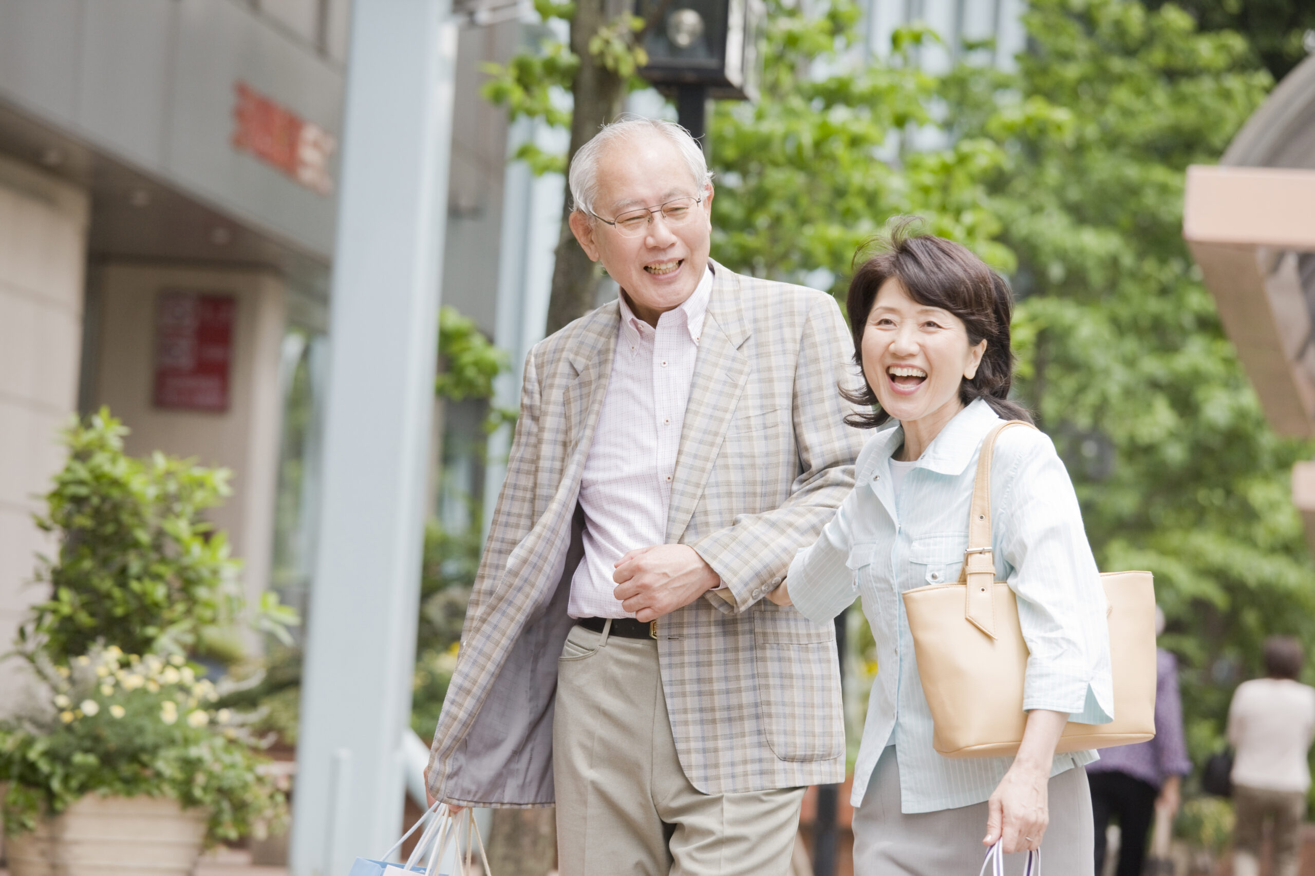 An elderly couple walking across the city arms crossed