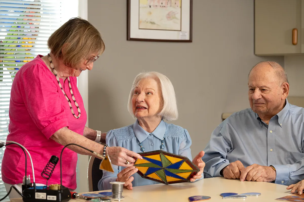 two women and a man working on stained glass project