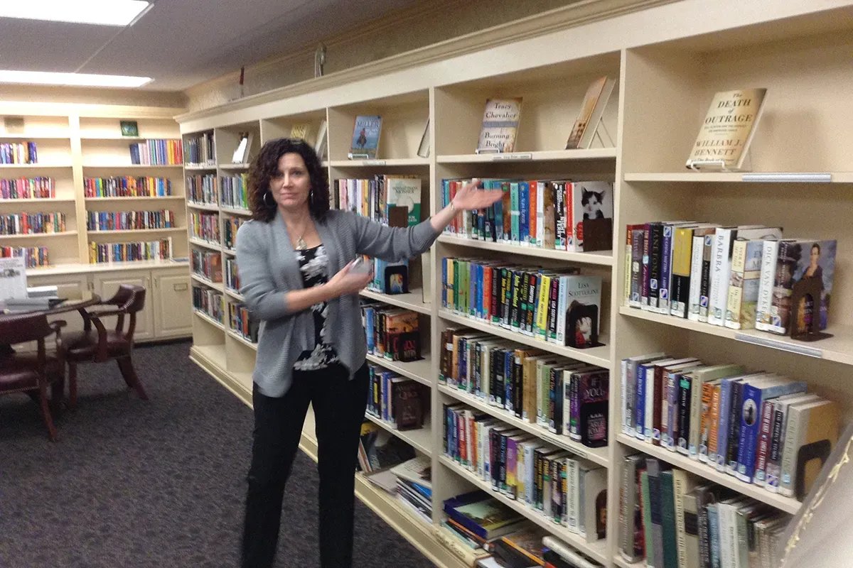 woman displaying shelves of books in the private library