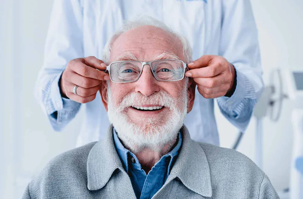 older gentleman smiling as doctor is fitting him for glasses