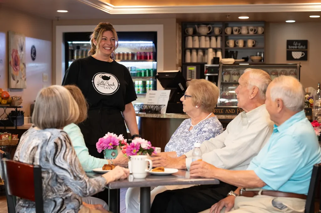 group of men and women sitting at a table in the cafe being visited by their waitress