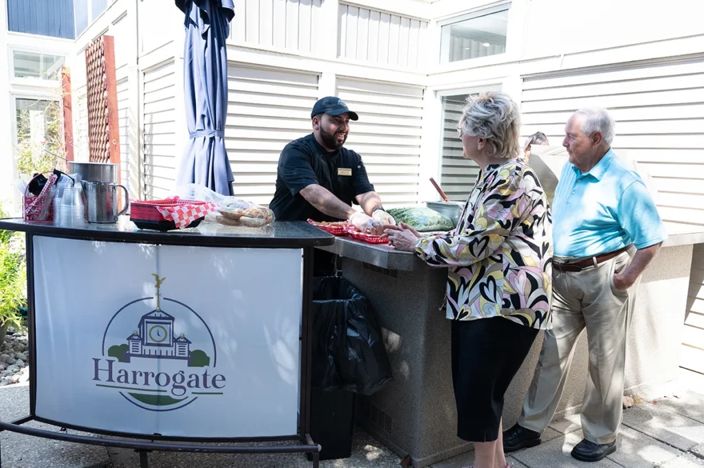 man and a woman getting food from a server on the terrace