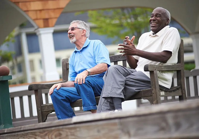 two gentlemen laughing together on a bench