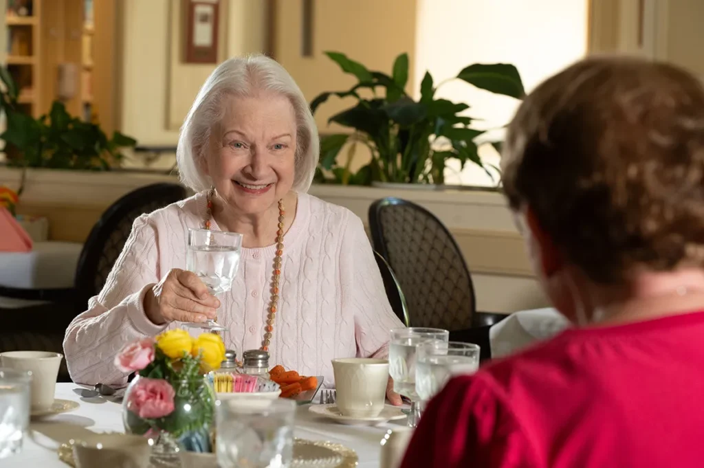 smiling woman holding a water glass in a dining room