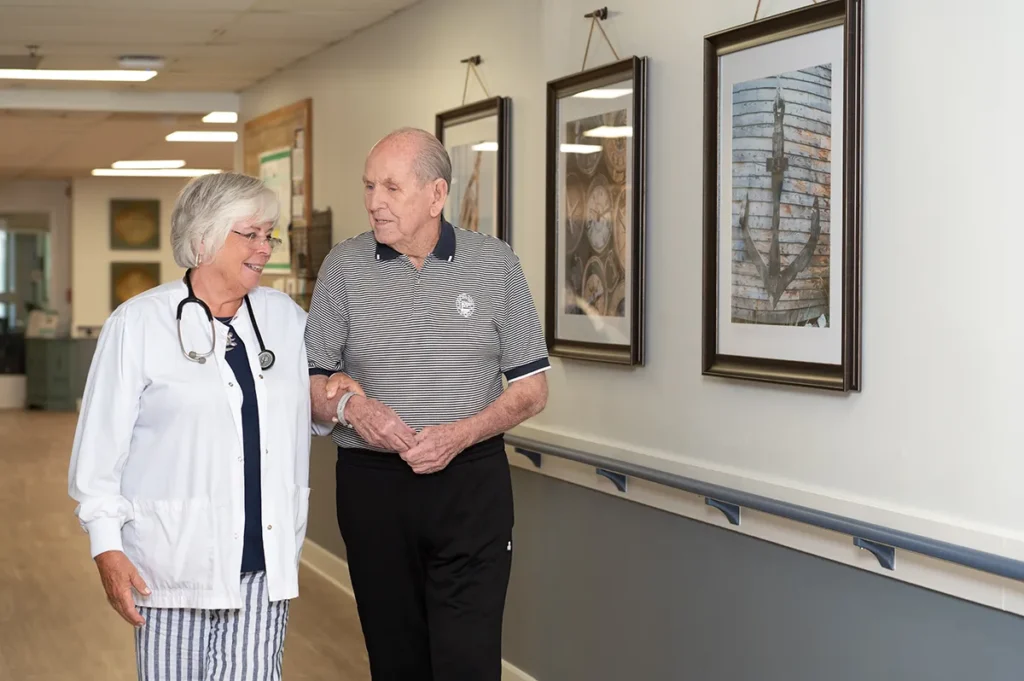 nurse walking an older gentleman down a hallway