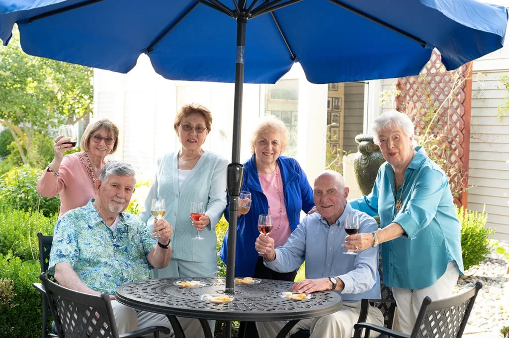 group of friends toasting at an outdoor table under an umbrella