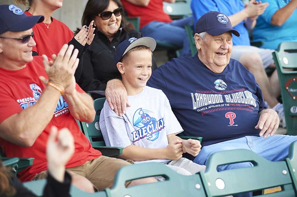 father, son and grandson sitting in the stands of a baseball game