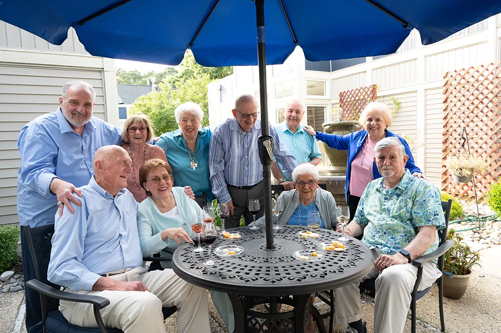 a group of men and women sitting outside at happy hour